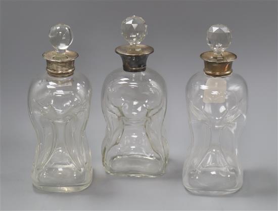 A pair of silver collared dimple moulded glass decanters and another with plated mount